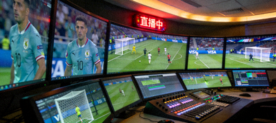 多屏幕体育直播控制室现场，显示着不同角度的足球比赛画面